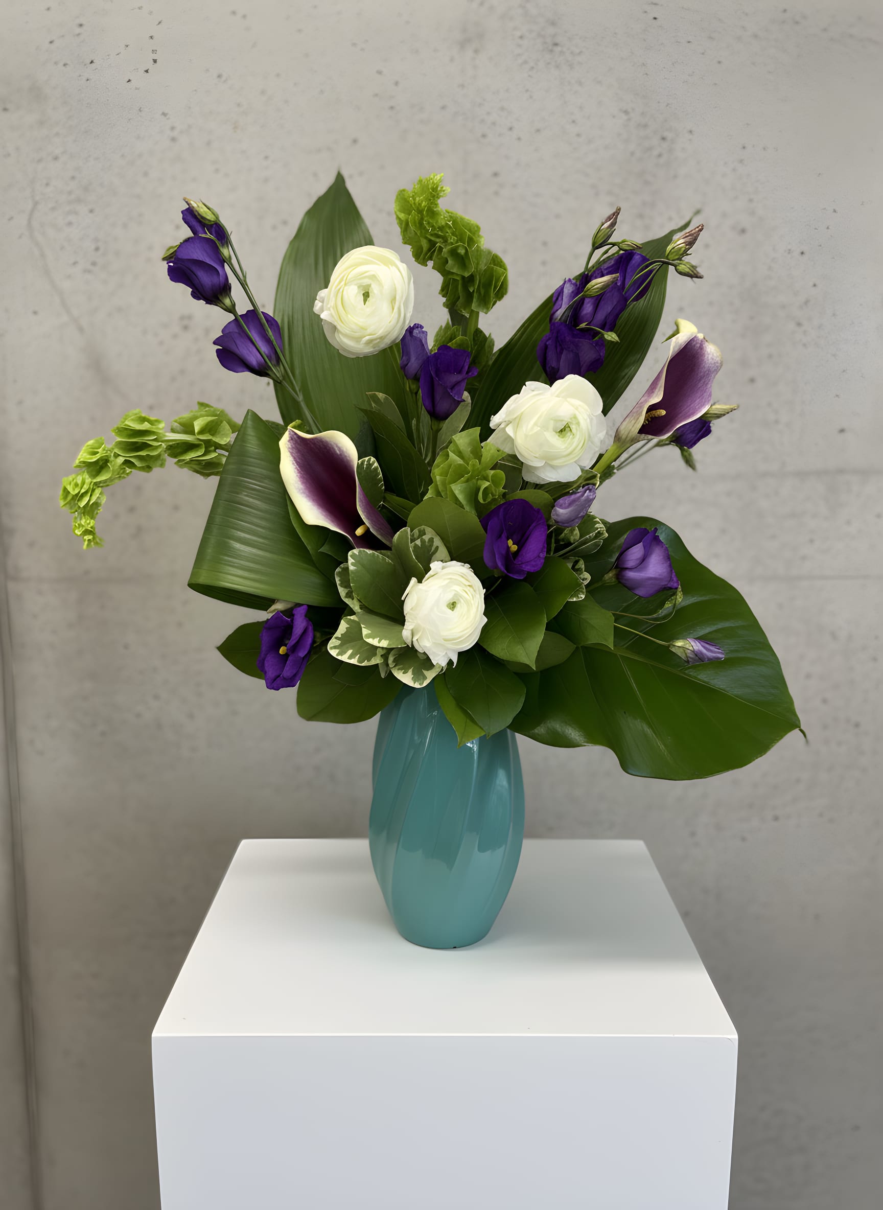 Monaco - Inspired by timeless European elegance, Monaco is a striking luxury flower arrangement designed to make a lasting impression. This modern floral design features elegant white ranunculus, rich purple lisianthus, graceful purple calla lilies, lush tropical foliage, and premium seasonal greenery, artfully arranged in a contemporary glass vase. With its sculptural lines and sophisticated color palette, Monaco is the perfect statement piece for life's most meaningful moments.  Whether you're celebrating a birthday, anniversary, new home, promotion, or sending a thoughtful sympathy or thank-you gift, Monaco offers a refined floral design that complements both modern and classic spaces. Every arrangement is handcrafted by the experienced designers at All Occasions Florist using the freshest flowers available, ensuring exceptional quality, long-lasting beauty, and a one-of-a-kind presentation.  As a trusted Dallas florist, All Occasions Florist proudly offers same-day flower delivery in Dallas, TX, including Highland Park, University Park, Preston Hollow, Uptown Dallas, Lakewood, Richardson, Plano, Garland, Irving, and surrounding communities. Whether you're sending flowers to a residence, office, hospital, funeral home, hotel, or special event, Monaco delivers sophistication with every stem.  Order Monaco online today from All Occasions Florist and discover why we're a trusted choice for luxury flower arrangements, same-day flower delivery, and premium floral design in Dallas.