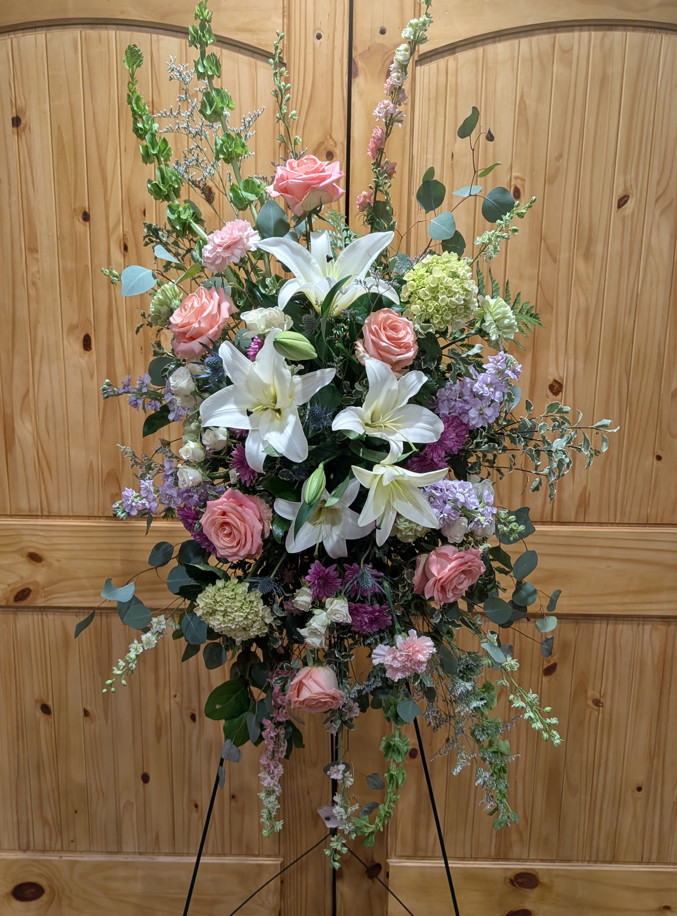 Fond Memories - Standing spray includes, White Lilies, Pink &amp; White  Roses, Hydrangeas, Violet Mums, Snapdragons, Bells of Ireland and assorted greens. 