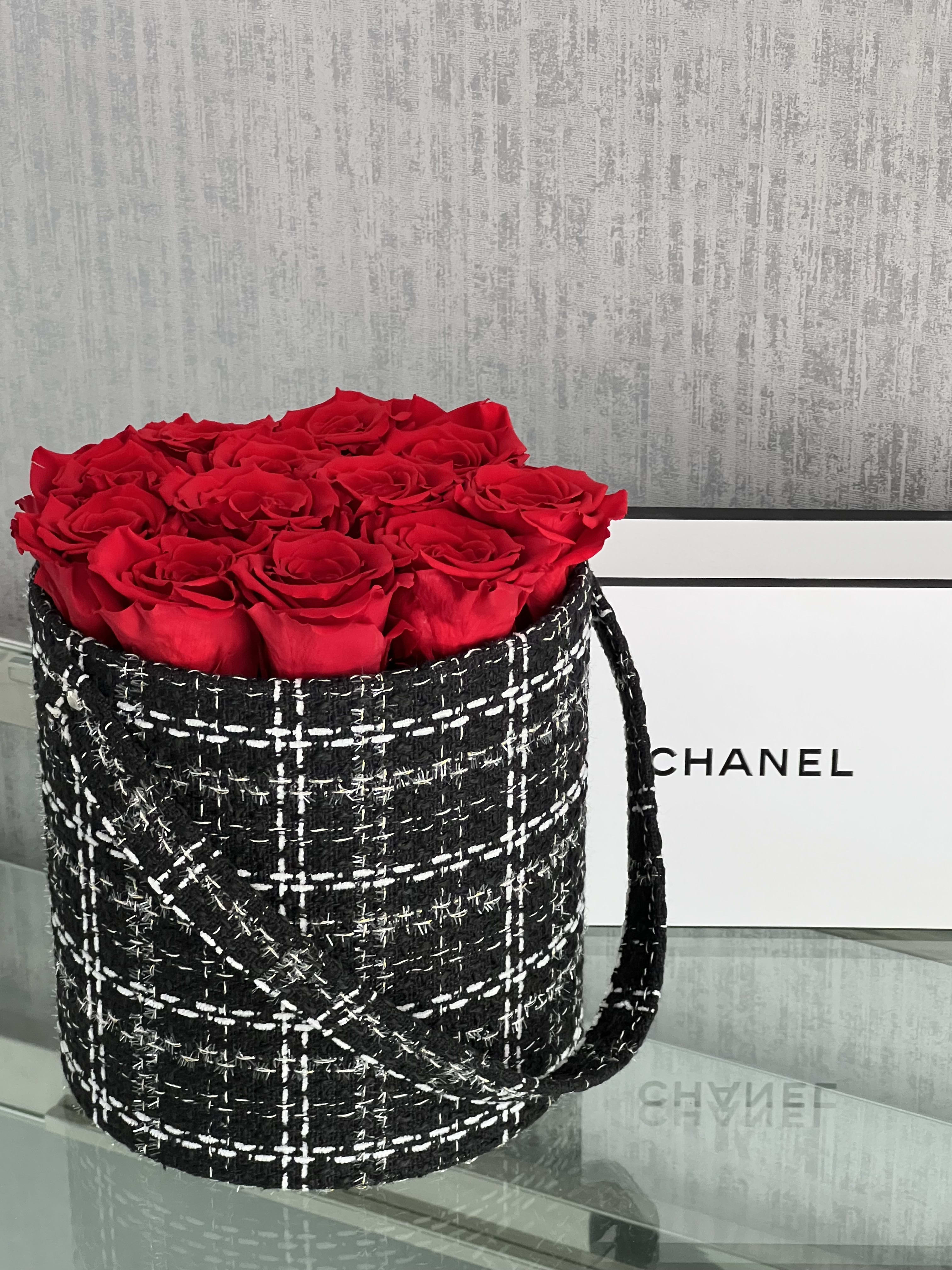 Red roses arranged in a black tweed-style round box with a handle