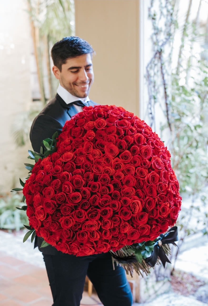 Man holding a large bouquet of red roses