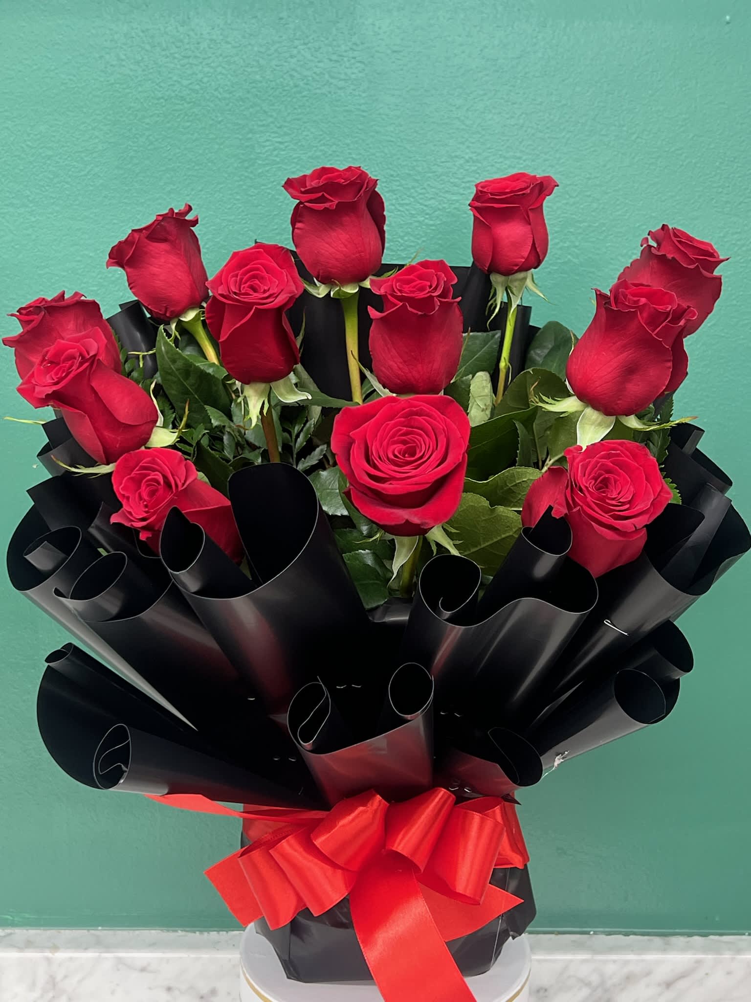 Bouquet of red roses wrapped in black paper with a red ribbon