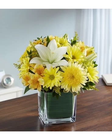 Yellow and white flower arrangement in a square glass vase