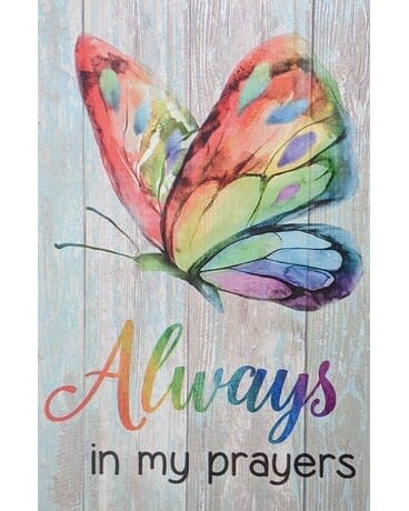 Decorative sign with a colorful butterfly and the words "Always in my prayers" on a wood-style background