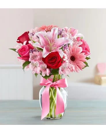 Pink and red mixed bouquet in a glass vase with a pink ribbon