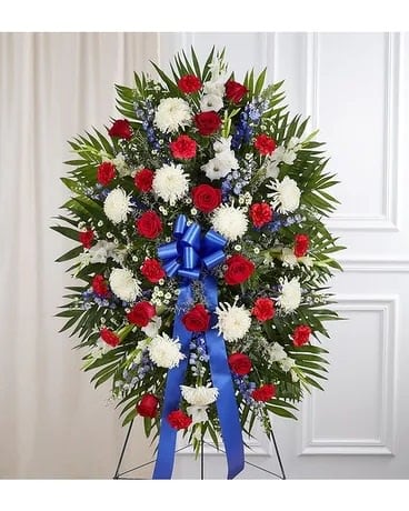 Standing floral spray with red and white flowers and a blue ribbon