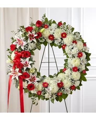Red and white floral wreath on a black stand with a red ribbon