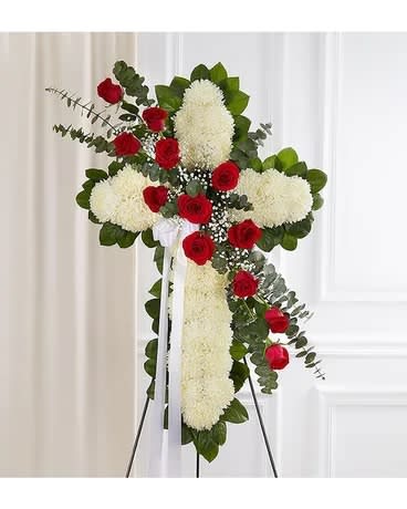 Standing floral cross with red roses and white blooms on an easel