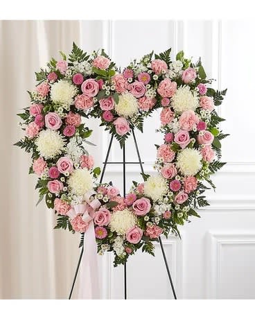 Heart-shaped floral wreath with pink and white flowers on a stand