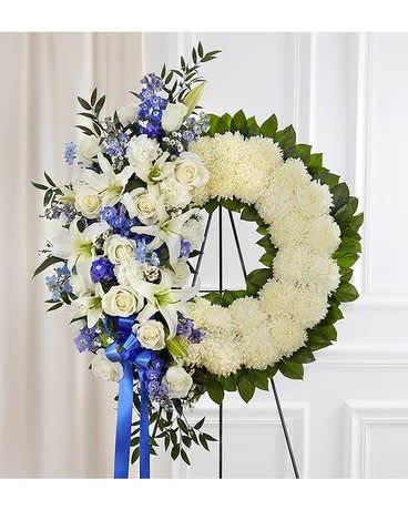 White and blue funeral wreath with roses and lilies on an easel