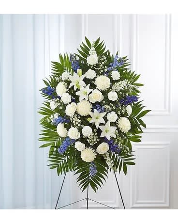 Standing funeral spray of white and blue flowers on an easel