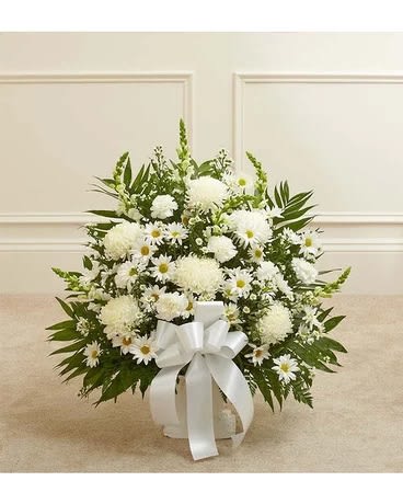 White floral arrangement in a white container with a ribbon bow