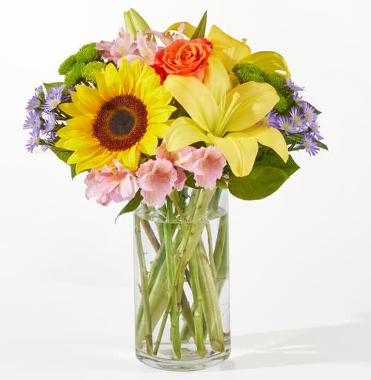 Bouquet of sunflowers, lilies, roses, and pink flowers in a glass vase