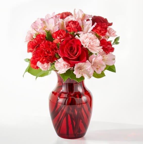 Red and pink flower bouquet in a red glass vase