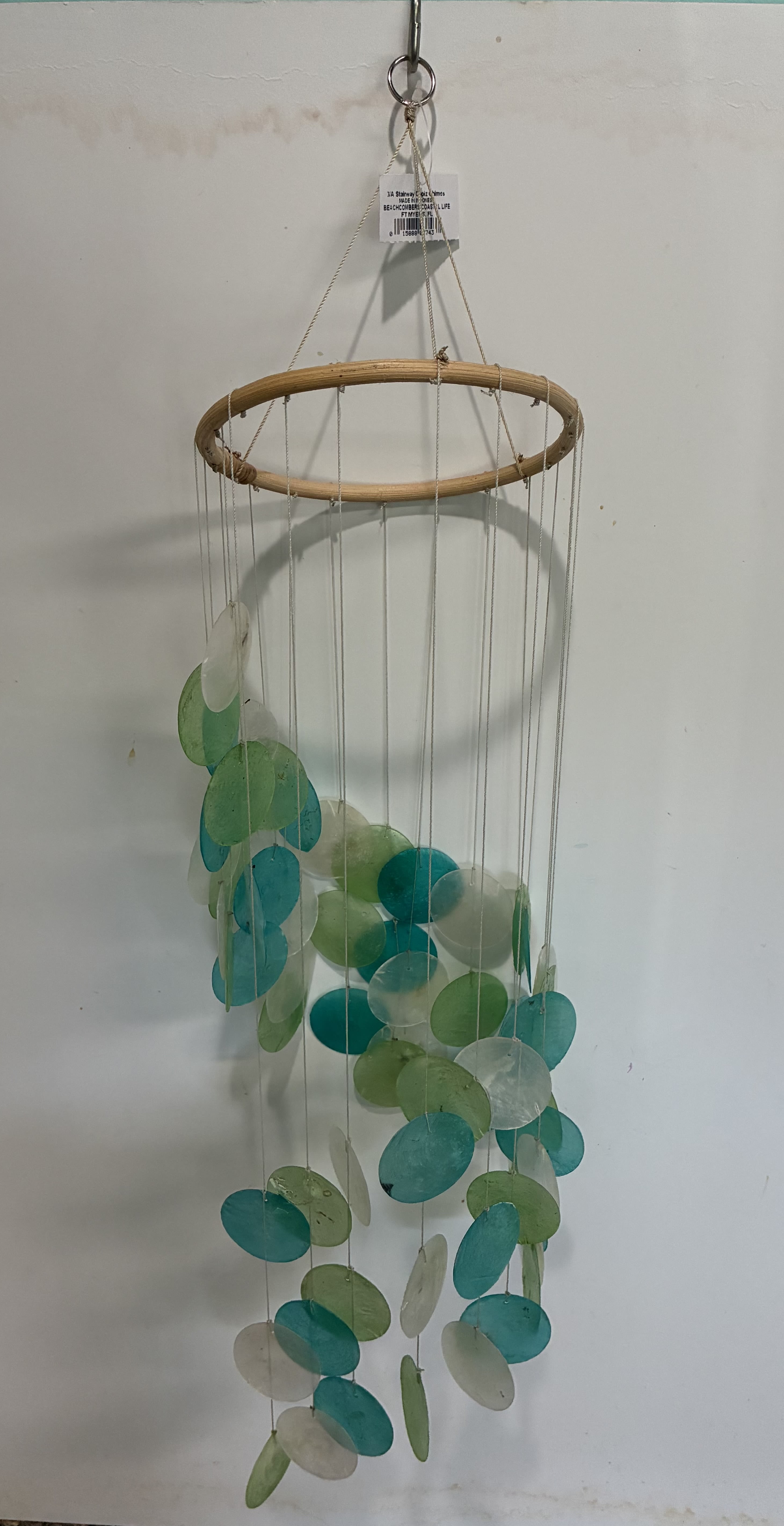 Hanging mobile with teal, green, and white discs on strings from a bamboo ring