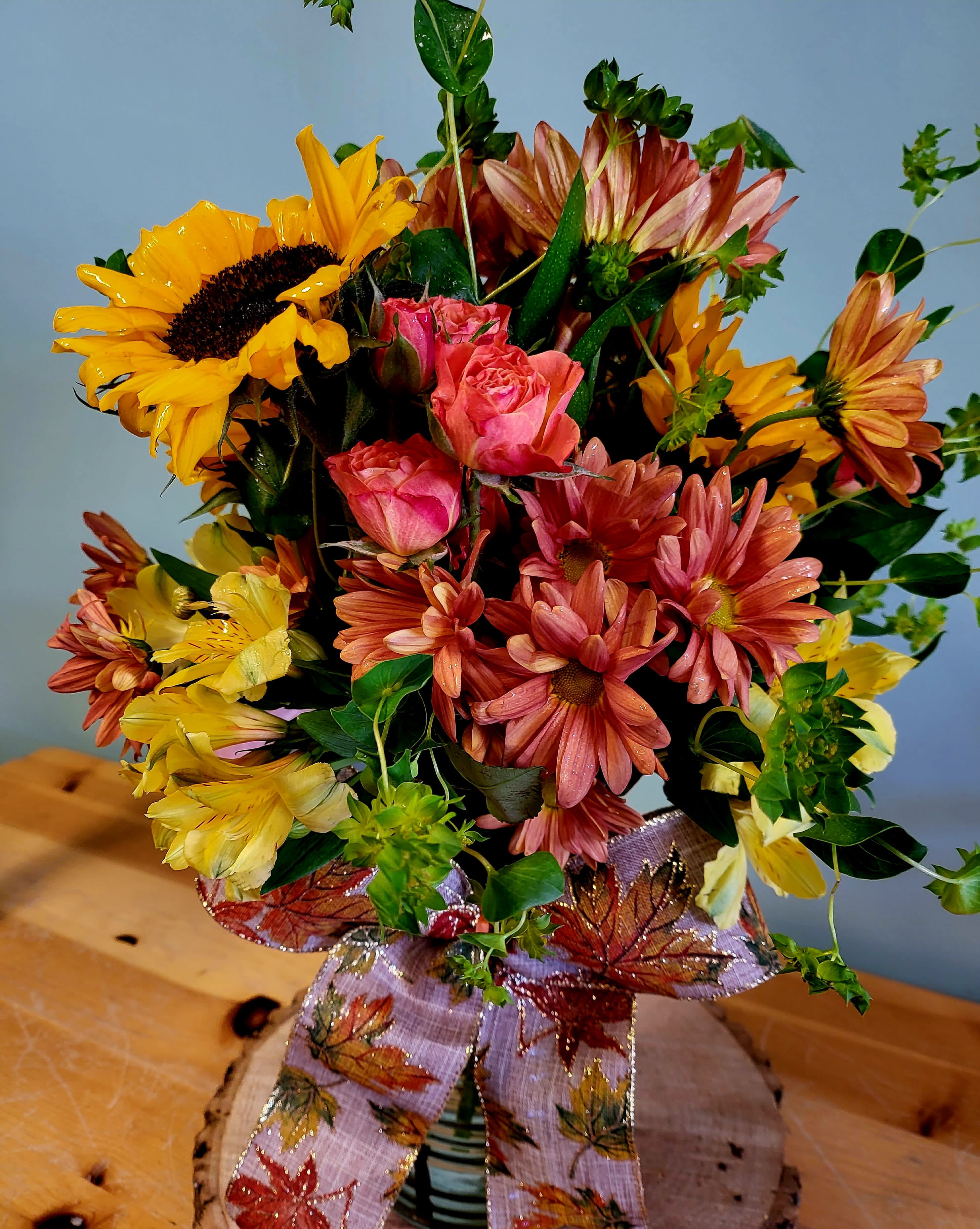 Bouquet of sunflowers, pink roses, and daisies with a decorative ribbon