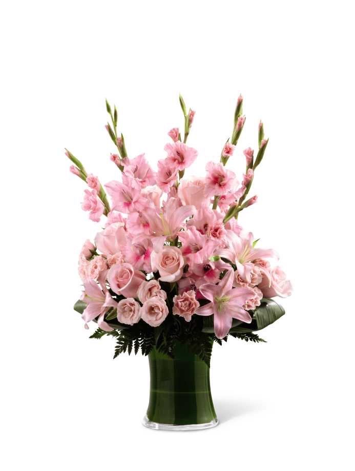 The FTD Lovely Tribute Bouquet - The FTD Lovely Tribute Bouquet is a warm and blushing display of peace and beauty, set to honor the deceased and bring comfort to family and friends. Pink gladiolus, pale pink roses, bi-color pink roses, pink Asiatic lilies and an assortment of lush greens create a sophisticated arrangement seated in a clear glass gathering vase, symbolizing your heartfelt love and sympathy.