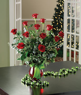 Red roses arranged in a red vase with a green ribbon