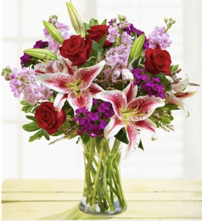 Bouquet of red roses and pink lilies in a clear glass vase