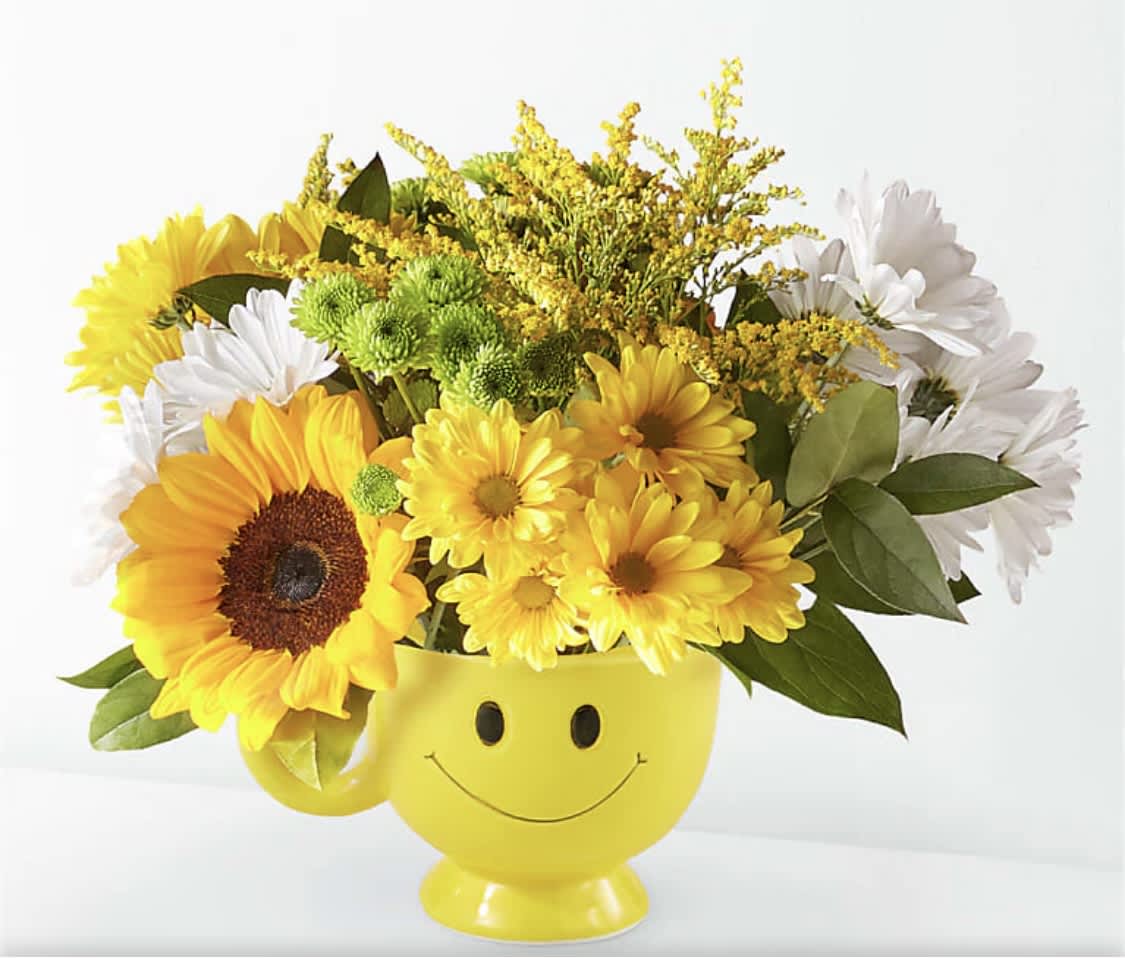 Yellow smiley-face mug filled with sunflowers and white daisies