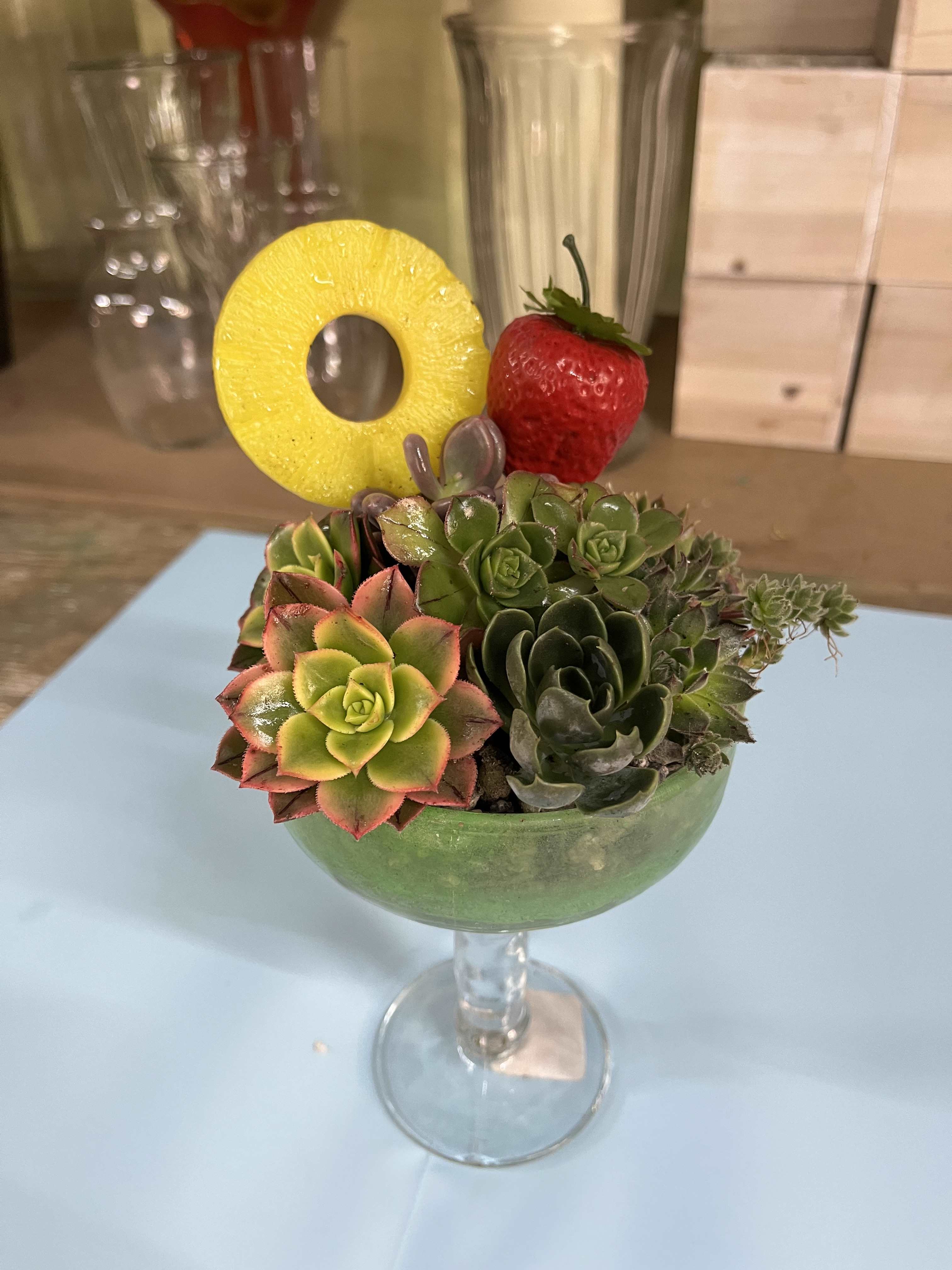 Succulent arrangement in a stemmed glass with a pineapple ring and strawberry garnish