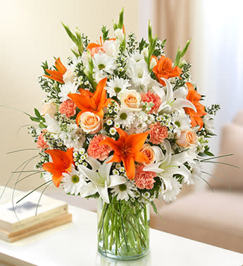  - Peach, Orange and White - Product ID: 95426   our bright and beautiful arrangement of lilies, roses, gladiolas, stock, daisy poms and more. Awash in soothing shades of peach, orange and white, it's hand-crafted by our florists in a classic vase for the home or service. Lush peach, orange and white arrangement of roses, lilies, gladiolas, stock, daisy poms, carnations and monte casino, accented with variegated pittosporum, salal, myrtle and bear grass Hand-designed by our select florists in a classic glass cylinder vase; vase measures 8"H Can be sent to the home of friends, family members or business associates, or to the funeral service Large arrangement measures approximately 24"H x 22"L Medium arrangement measures approximately 22"H x 20"L Small arrangement measures approximately 20"H x 18"L Our florists hand-design each arrangement, so colors, varieties, and container may vary due to local availability Lilies may arrive in bud form and will open to full beauty over the next 2-3 days