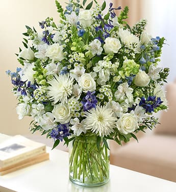  Sorrow - Blue and White - Product ID: 95410   Beautiful in blue and white, our abundant sympathy arrangement makes a fitting remembrance during difficult times. Elegant roses, snapdragons, delphinium, stock, alstroemeria, spider mums and more are tastefully arranged by our florists in a classic glass vase. Lush blue and white arrangement of roses, snapdragons, delphinium, stock, alstroemeria, spider mums and monte casino, accented with variegated pittosporum and ruscus Hand-designed by our select florists in a classic glass cylinder vase; vase measures 8"H Can be sent to the home of friends, family members or business associates, or to the funeral service Large arrangement measures approximately 24"H x 22"L Medium arrangement measures approximately 22"H x 20"L Small arrangement measures approximately 20"H x 18"L Our florists hand-design each arrangement, so colors, varieties, and container may vary due to local availability