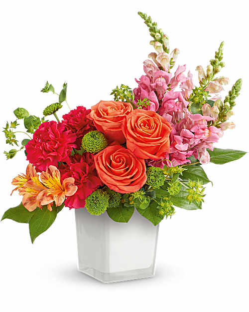 Mixed bouquet of orange roses, pink flowers, and green accents in a clear vase