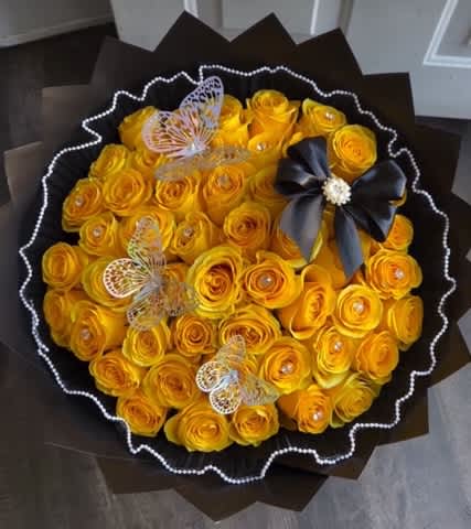 Bouquet of yellow roses with butterfly decorations and a black ribbon