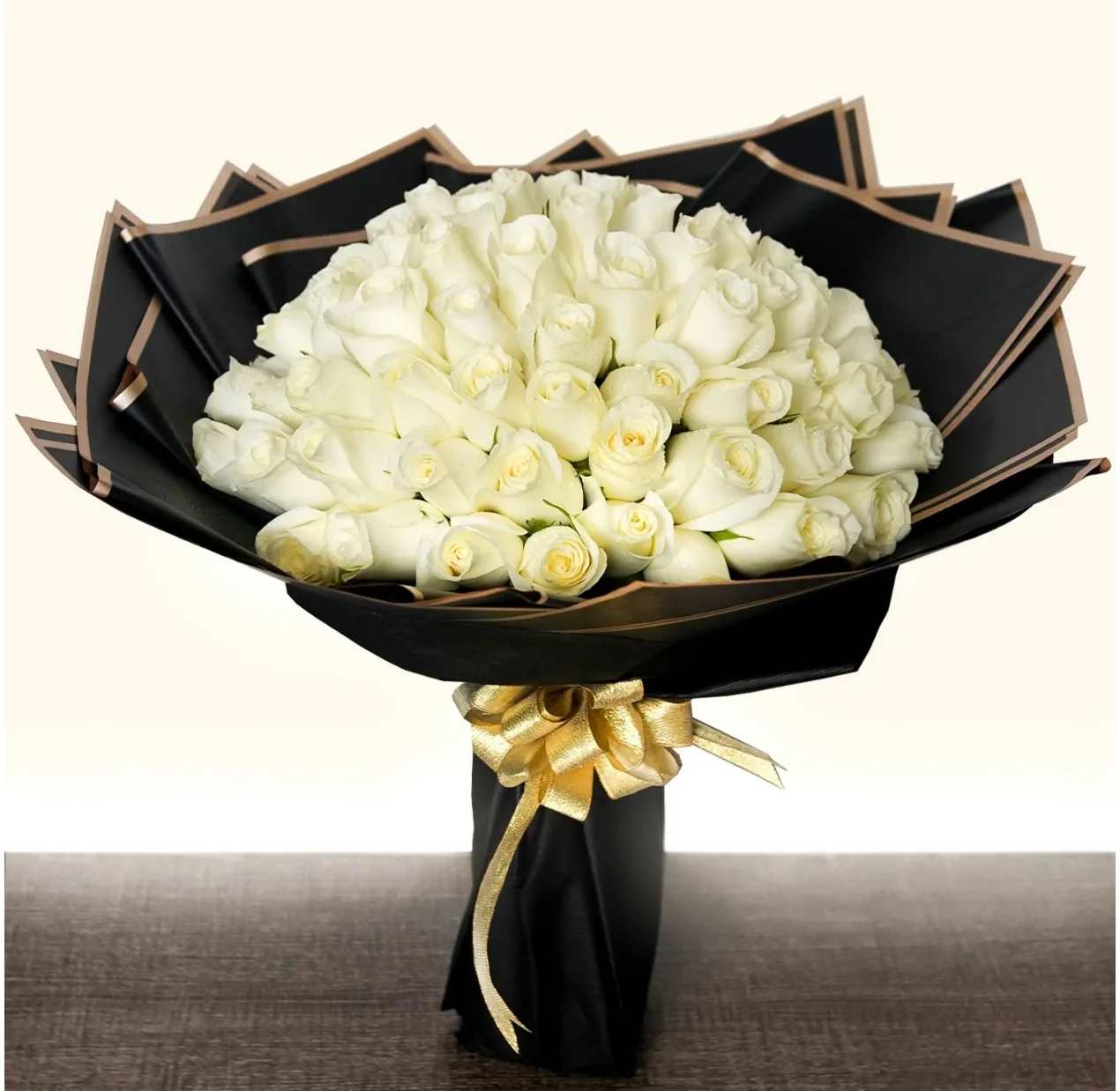 Bouquet of white roses wrapped in black paper with a gold ribbon