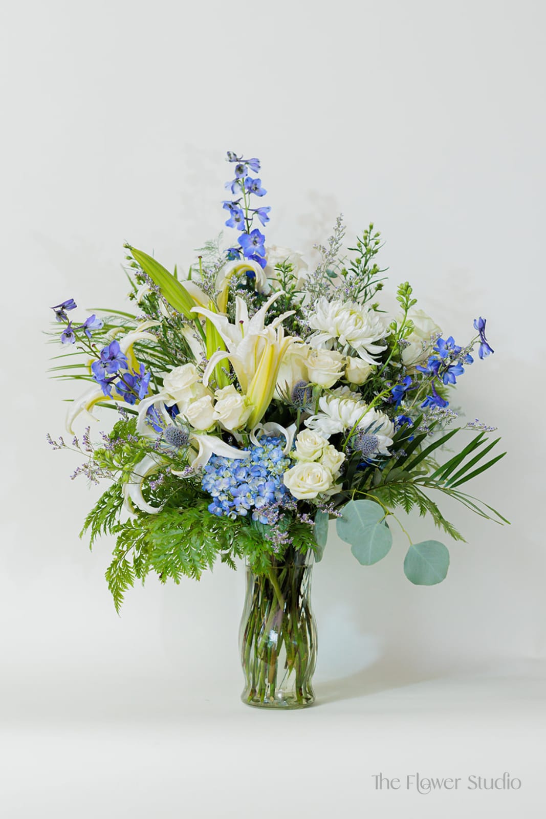 Blue and white mixed flower arrangement in a glass vase
