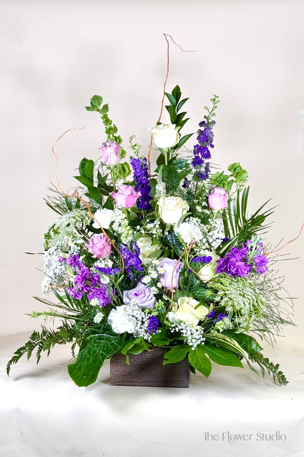 Tall mixed bouquet of roses and purple flowers in a wooden box