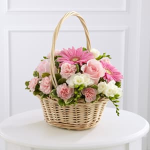 Pink and white flowers arranged in a wicker basket with a handle