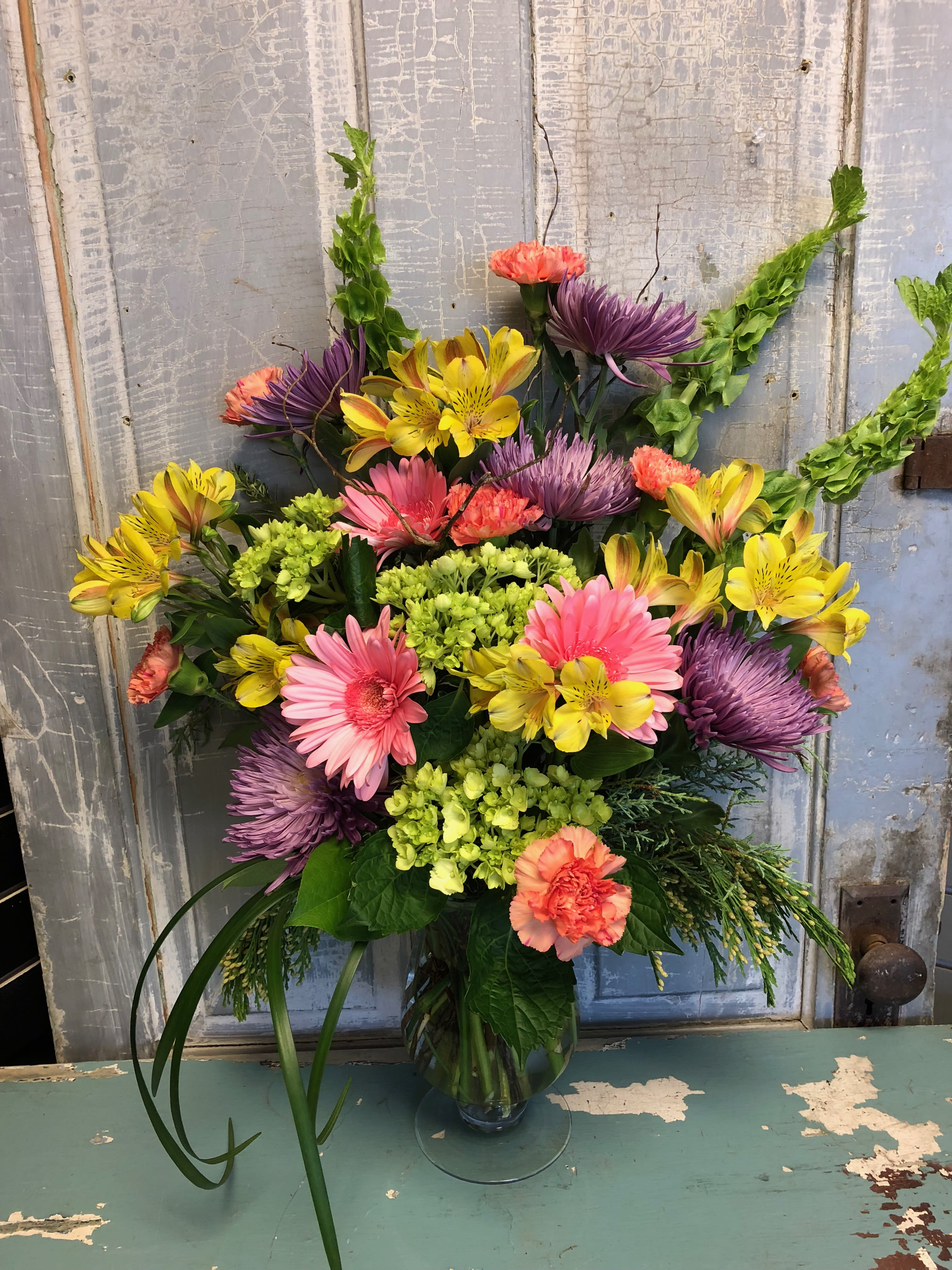 Colorful mixed bouquet in a glass vase with pink, yellow, purple, and coral blooms