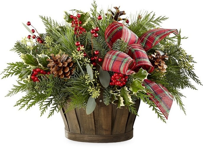 Holiday arrangement in a wooden basket with plaid ribbon and pinecones