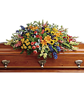 Colorful casket spray with mixed flowers on a wooden coffin