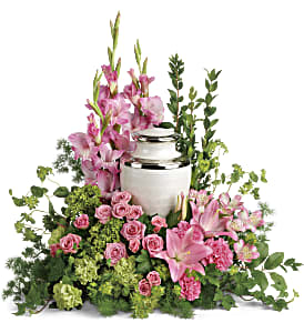 Pink flowers arranged around a white urn with greenery