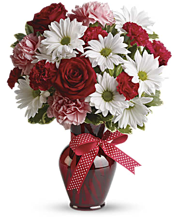 Red and white bouquet in a red glass vase with a polka-dot ribbon