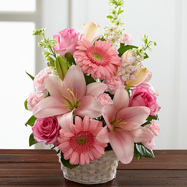 Pink lilies, roses, and gerbera daisies in a woven basket