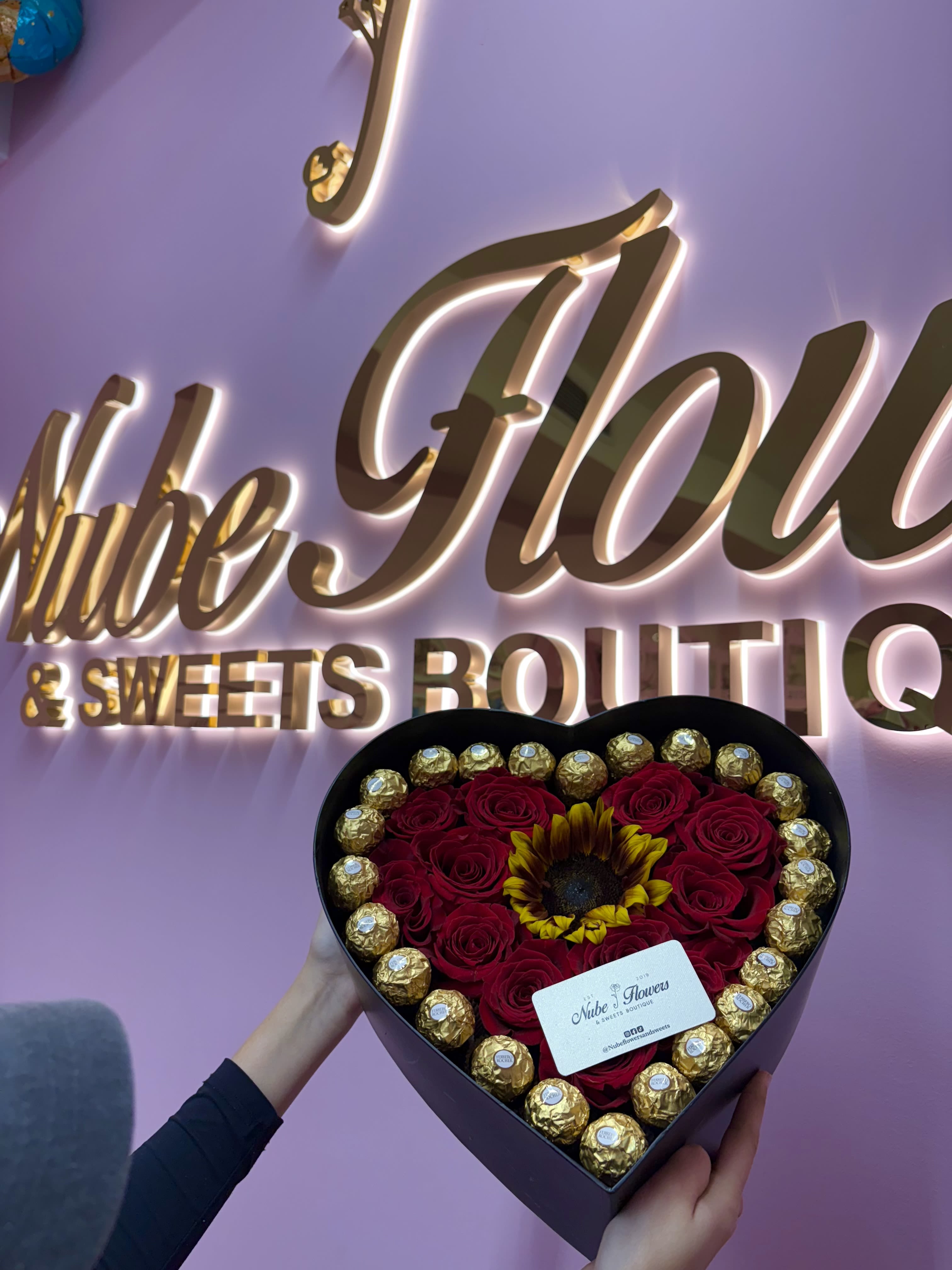 Heart-shaped box of red roses with a sunflower and gold chocolates