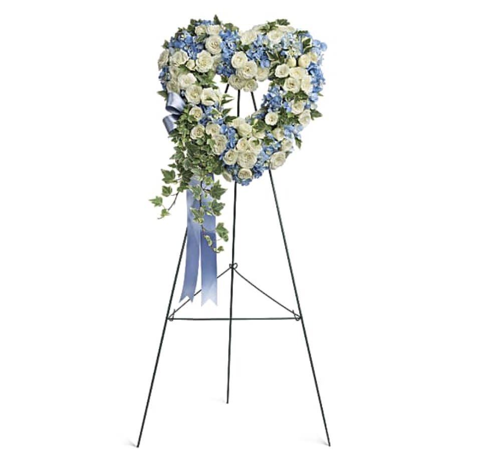 Heart-shaped floral wreath on a standing easel with blue and white flowers