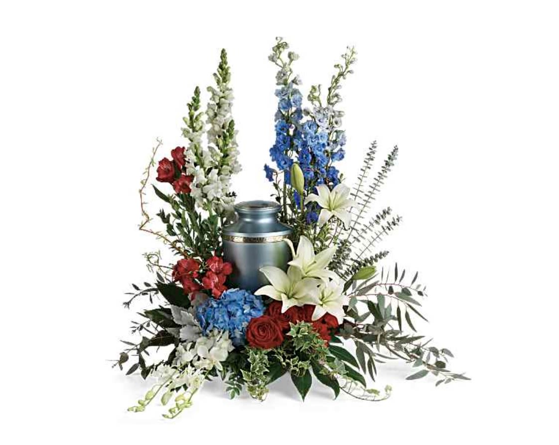 Reflections Of Honor Cremation Tribute - White lilies, red roses, blue hydrangeas and delphinium framed around a metal urn; a dignified patriotic tribute with cascading orchids and soft greenery for memorial services.
