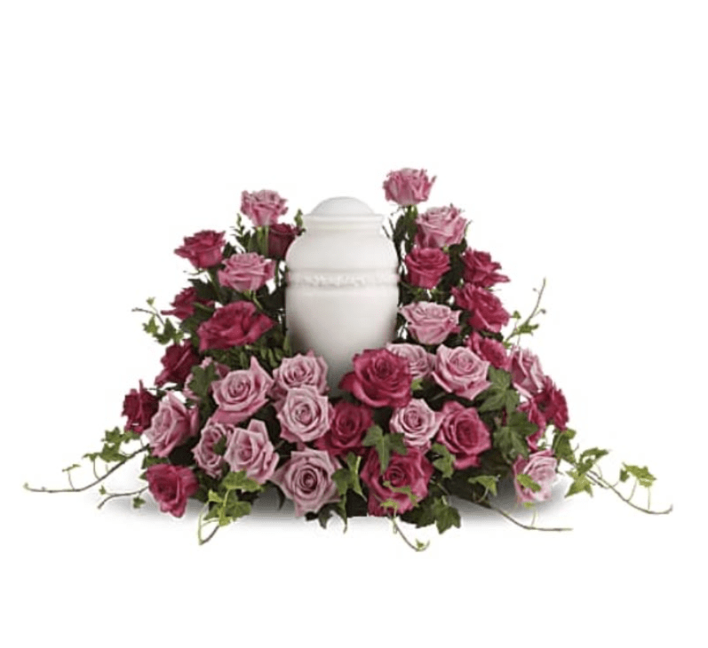 Bed of Pink Roses - Pink and mauve roses in a low, circular collar around a white ceramic urn, softened with trailing ivy-tender, serene sympathy arrangement for memorials or honoring a loved one.