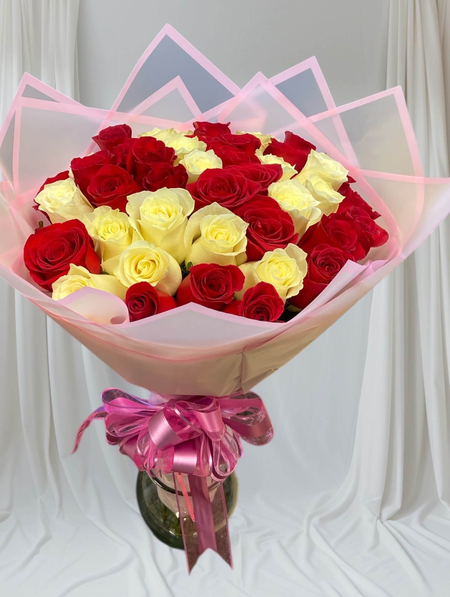 Bouquet of red and pale yellow roses wrapped in pink paper
