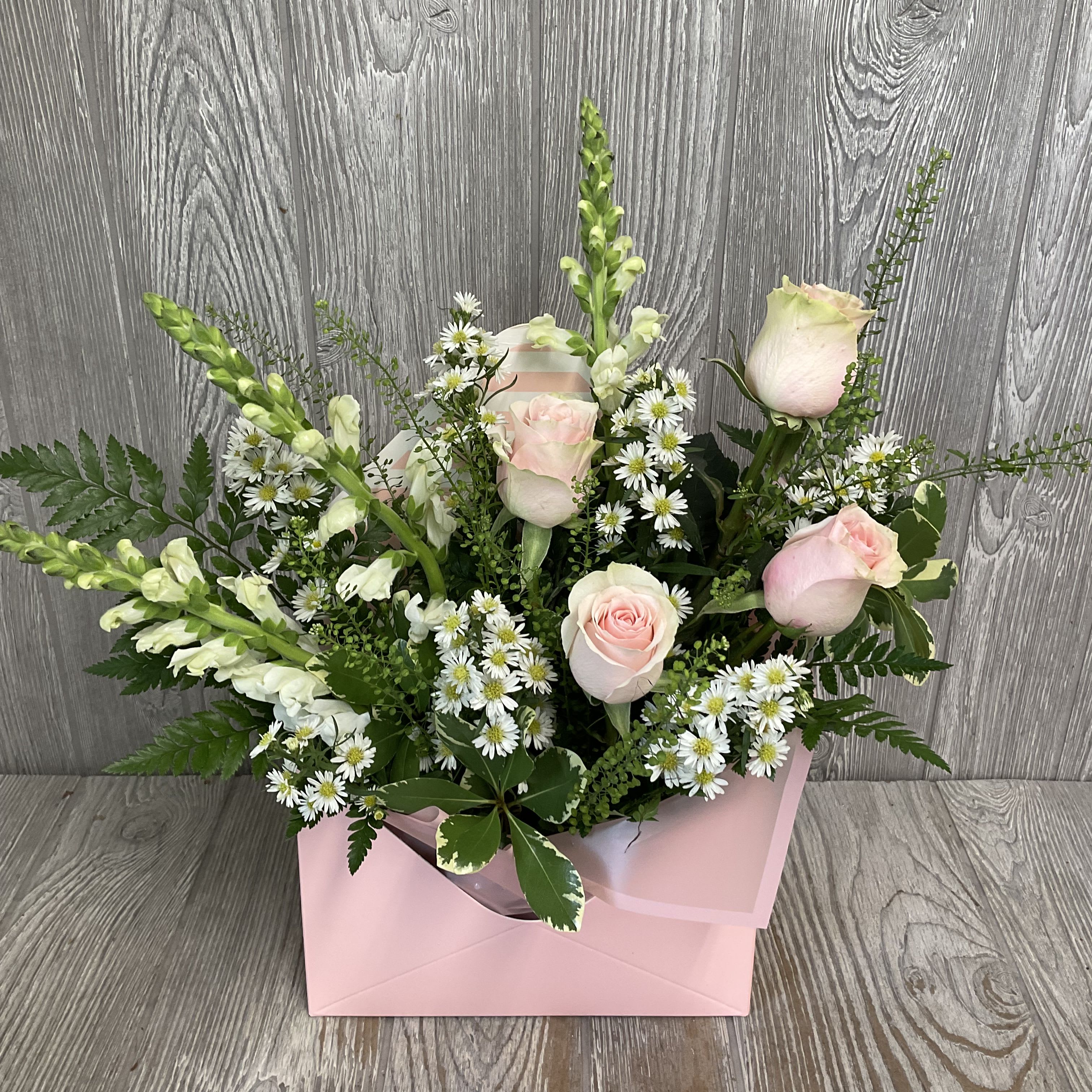 Letters to Mom - Pinks - A beautiful arrangement of fresh cut flowers arranged in an envelope style container. Perfect to send some cheer this Mother’s Day. Flowers and colors may vary, envelope container in assorted pinks. 