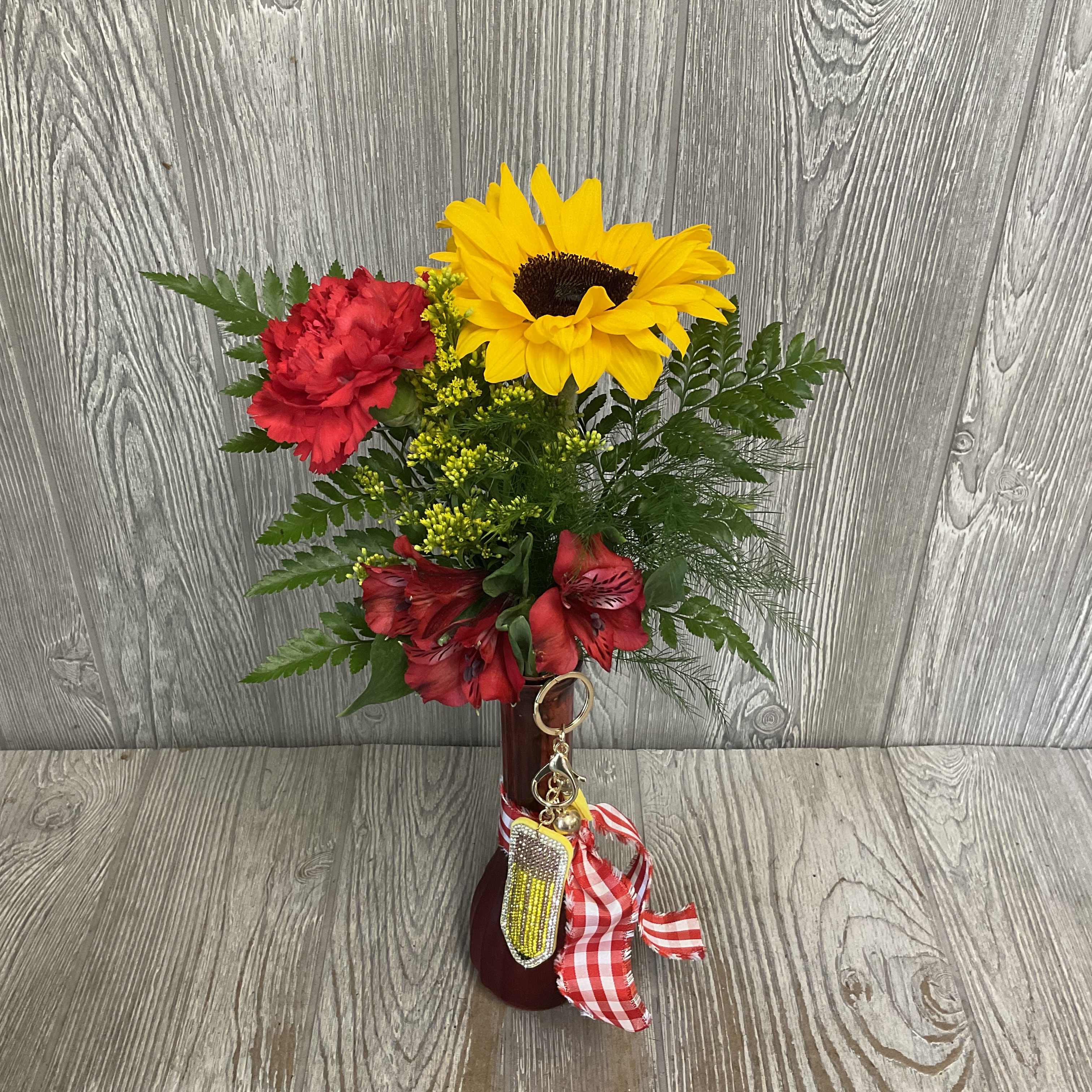 Red and yellow flower arrangement in a burgundy vase with a gingham ribbon