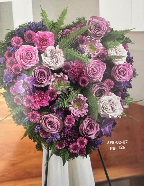Heart-shaped bouquet of pink, purple, and white flowers on an easel