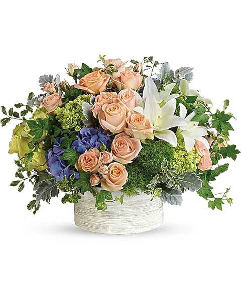 Peach roses and white lilies in a low white container