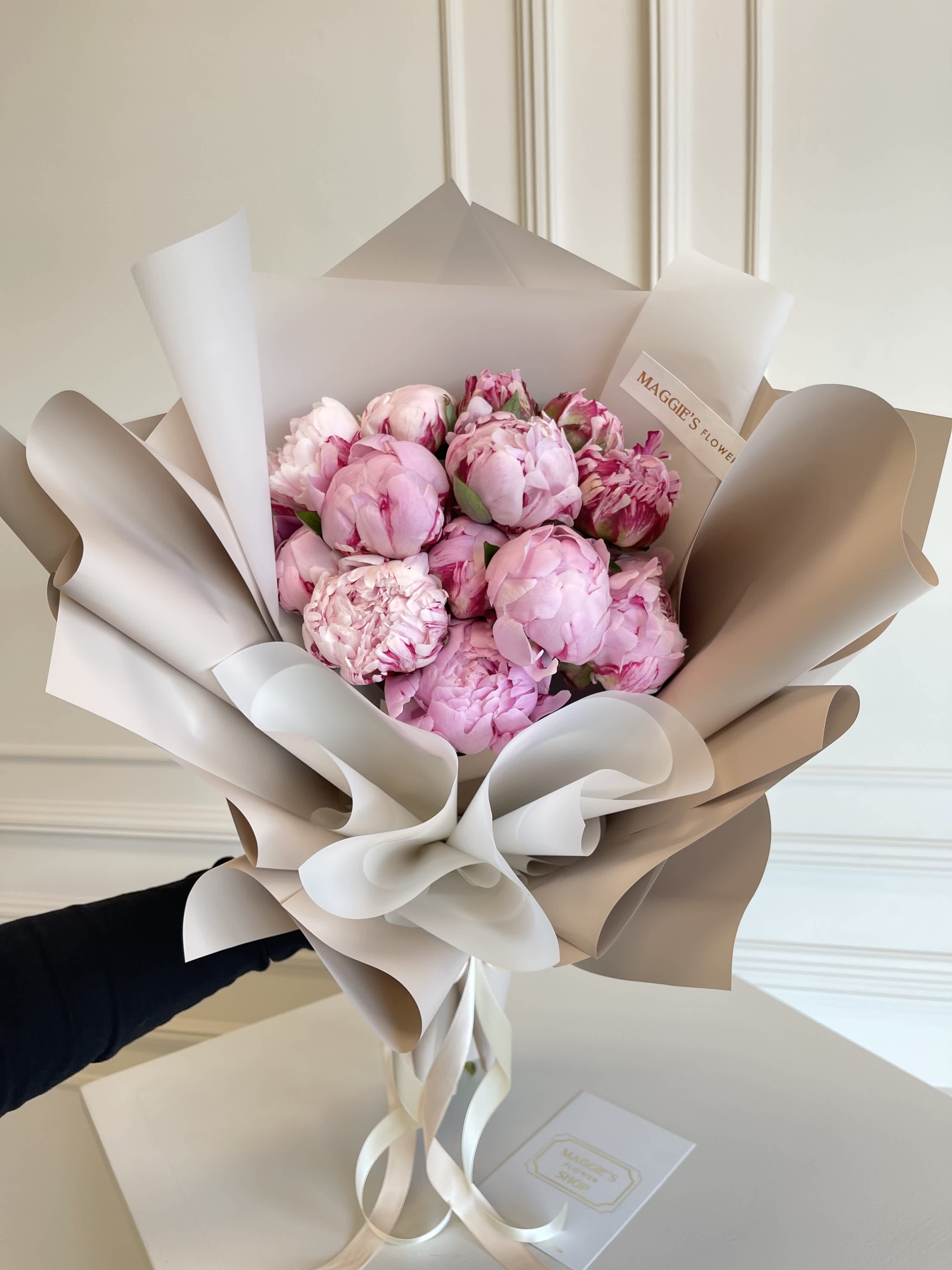 Bouquet of pink peonies wrapped in beige and white paper