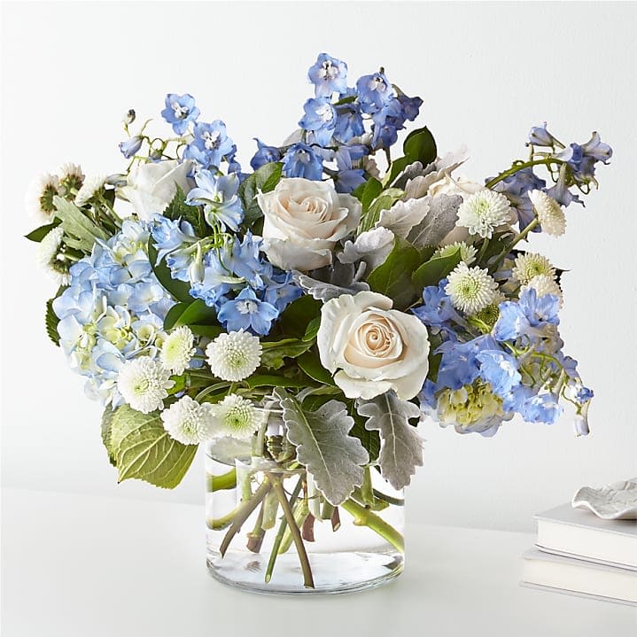 Blue and white flower arrangement in a clear glass vase