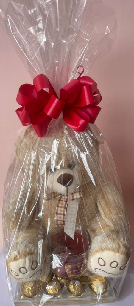 Teddy bear gift basket wrapped in clear plastic with a red bow
